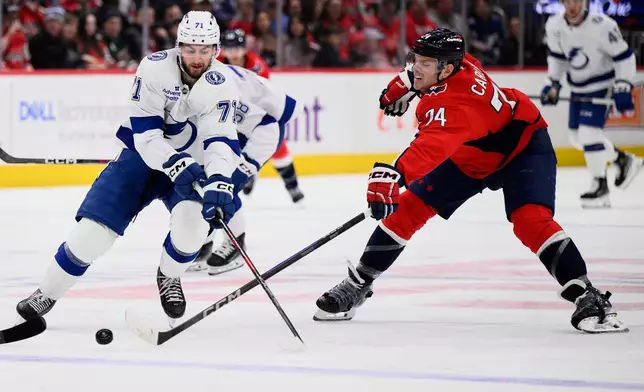 Tampa Bay Lightning center Anthony Cirelli (71) and Washington Capitals defenseman John Carlson (74) battle for the puck during the second period of an NHL hockey game, Saturday, March 1, 2025, in Washington. (AP Photo/Nick Wass)