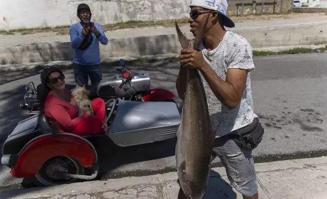 A fisherman carries his catch of the day after using a makeshift "corcho" raft in Cojimar, east of Havana, Cuba, Wednesday, March 12, 2025. (AP Photo/Ramon Espinosa)
