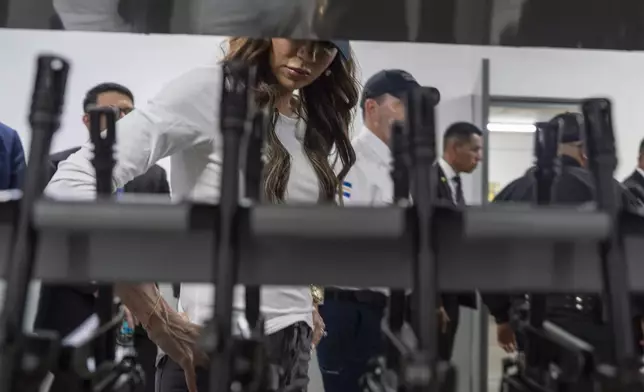 Homeland Security Secretary Kristi Noem looks at rifles in the armory during a tour of the Terrorist Confinement Center in Tecoluca, El Salvador, Wednesday, March 26, 2025. (AP Photo/Alex Brandon)