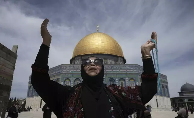 A woman prays next to the Dome of the Rock Mosque in the Al-Aqsa Mosque compound on the fourth Friday prayers of the Muslim holy month of Ramadan in the Old City of Jerusalem, Friday, March 28, 2025. (AP Photo/Mahmoud Illean)