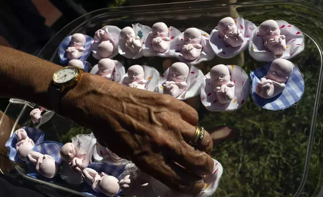 An organizer arranges figurines of fetuses that will be given out to demonstrators marching in defense of human life from the moment of conception, in a protest against Argentina’s progressive policy on abortion rights, in Buenos Aires, Saturday, March 29, 2025. (AP Photo/Rodrigo Abd)