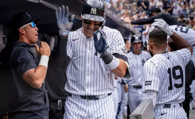 New York Yankees' Aaron Judge (99) celebrates in the dugout after hitting a grand slam in the third inning of a baseball game against the Milwaukee Brewers, Saturday, March 29, 2025, in New York. (AP Photo/Angelina Katsanis)