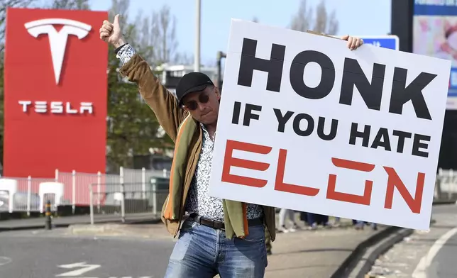 A protester holds a placard as he takes part in the Tesla Takedown Global Day of Action near a Tesla dealership in London, Saturday, March 29, 2025.(AP Photo/Thomas Krych)