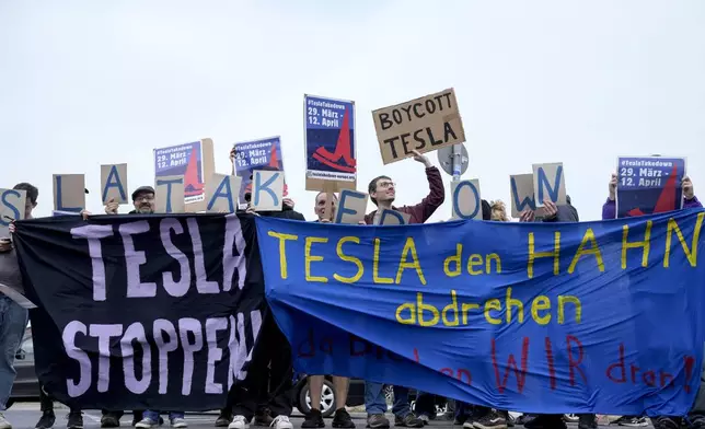 Protesters attend the Tesla Takedown Global Day of Action in front of a Tesla dealership, in Berlin, Saturday, March 29, 2025. (AP Photo/Ebrahim Noroozi)
