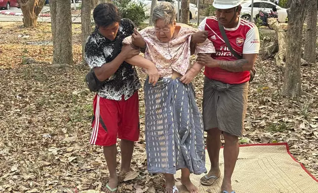 Rescue workers help an injured women who was trapped under a building Friday, March 28, 2025, in Naypyitaw, Myanmar. (AP Photo/Aung Shine Oo)