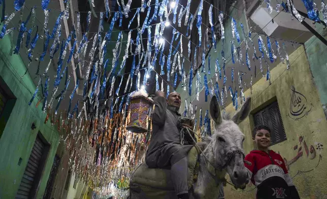 55-year-old "musaharati," or "dawn caller" Essam Sayed, rides his donkey to wake people up for a meal before sunrise, during the Islamic holy month of Ramadan, in the Arab Ghoneim district of Helwan on the southern outskirts of Cairo, Egypt, Saturday, March 15, 2025.(AP Photo/Amr Nabil)