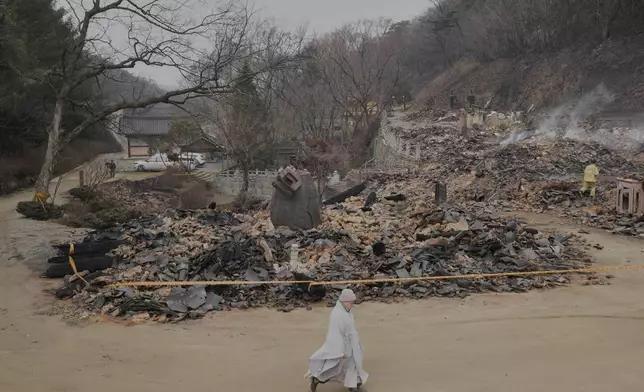A Buddhist monk passes by the remains of the bell pavilion at Gounsa Temple in Uiseong, South Korea, Friday, March 28, 2025. (AP Photo/Ahn Young-joon)