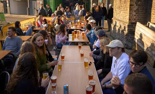 Customers take a beer outside the Hiver Beers bar and brewery on the Bermondsey Beer Mile in south London, Saturday March 8, 2025. (AP Photo/Tony Hicks)
