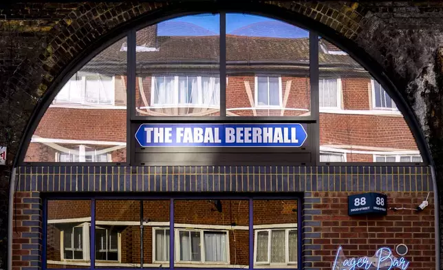 The windows of a residential apartment block are reflected in the windows of the Fabal Beerhall on Druid Street on the Bermondsey Beer Mile in south London, Saturday March 8, 2025. (AP Photo/Tony Hicks)