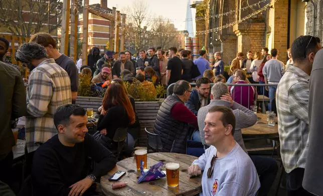 People sit in the sun outside a bar on the Bermondsey Beer Mile in south London, Saturday March 8, 2025. (AP Photo/Tony Hicks)