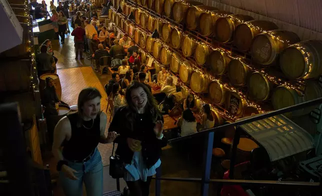 Customers climb the stairs to the upper level of the Barrel Project, a bar on the Bermondsey Beer Mile in south London, Saturday March 8, 2025. (AP Photo/Tony Hicks)
