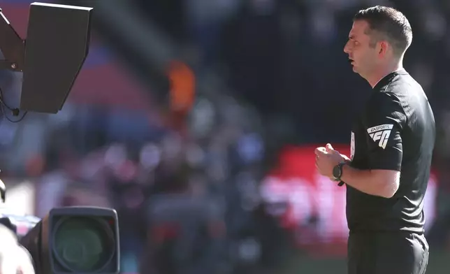 Referee Michael Oliver pauses the match and asks for the VAR to check on a possible goal during the English FA Cup soccer match between Crystal Palace and Millwall at Selhurst Park, London, England, Saturday, March 1, 2025. (AP Photo/Ian Walton)