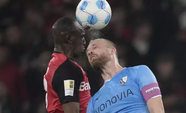 Leverkusen's Nordi Mukiele, left, and Bochum's Philipp Hofmann jump for the ball during the German Bundesliga soccer match between Bayer Leverkusen and VfL Bochum at the BayArena in Leverkusen, Germany, Friday, March 28, 2025. (AP Photo/Martin Meissner)