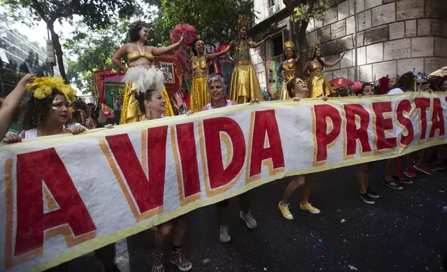 Revelers hold a banner that reads in Portuguese; "Life is worth it," in tribute to Brazilian actress Fernanda Torres, who's competing for the best actress Oscar for her role in "I'm Still Here", at the "Cordao do Boitata" street pre-carnival party in Rio de Janeiro, Sunday, Feb. 23, 2025. (AP Photo/Bruna Prado)