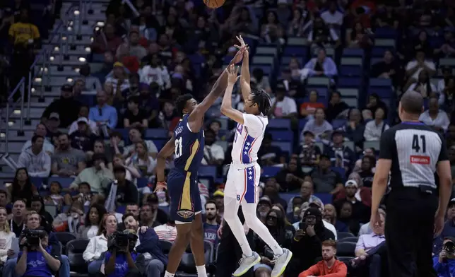 Philadelphia 76ers guard Jeff Dowtin Jr. (11) gets a shot off after slipping against New Orleans Pelicans center Yves Missi (21) during the first half of an NBA basketball game in New Orleans, Monday, March 24, 2025. Dowtin grabbed his knee after the play. (AP Photo/Matthew Hinton)