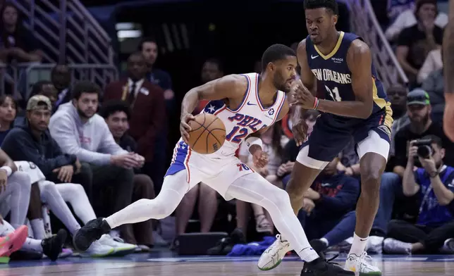 Philadelphia 76ers guard Jared Butler (12) dribbles against New Orleans Pelicans center Yves Missi (21) during the first half of an NBA basketball game in New Orleans, Monday, March 24, 2025. (AP Photo/Matthew Hinton)