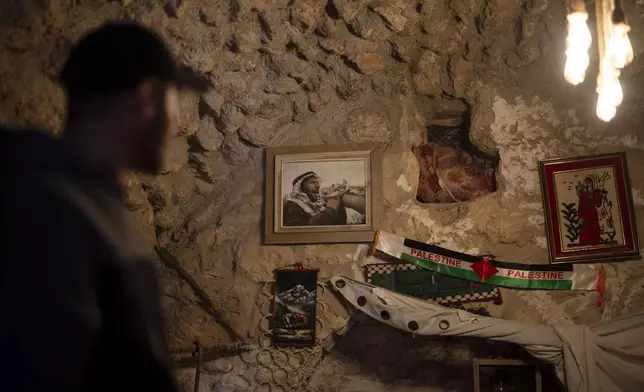 Salem Adra, brother of Palestinian activist Basel Adra, who won Best Documentary Feature at the Oscars for "No Other Land", looks at the photo of their father, hanging on a wall at a house where they usually gather for meetings at the West Bank village of Tuwani, Monday, March 3, 2025. (AP Photo/Leo Correa)