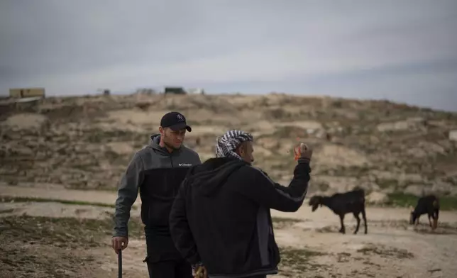 Salem Adra, left, brother of Palestinian activist Basel Adra, who won Best Documentary Feature at the Oscars for "No Other Land" talks with a local Palestinian shepherd as they stand near an Israeli settlers' outpost at the West Bank village of Tuwani, Monday, March 3, 2025. (AP Photo/Leo Correa)