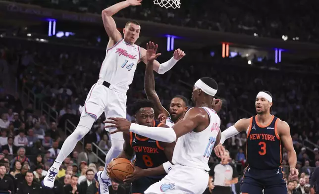 New York Knicks forward OG Anunoby (8) is surrounded by Miami Heat defenders, including center Bam Adebayo (13) and guard Tyler Herro (14), during the first half of an NBA basketball game, Monday, March 17, 2025, in New York. (AP Photo/Heather Khalifa)