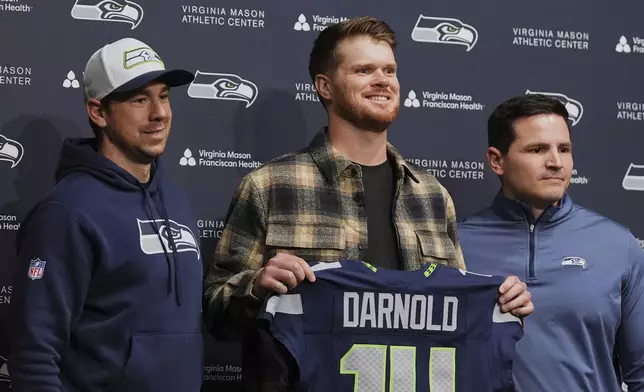 Seattle Seahawks quarterback Sam Darnold, center, poses for a photo with offensive coordinator Klint Kubiak, left, and head coach Mike Macdonald, right, during an introductory press conference Thursday, March 13, 2025, at the NFL football team's facilities in Renton, Wash. (AP Photo/Lindsey Wasson)