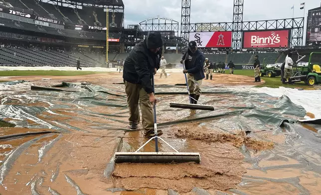 The grounds crew works on the field during a rain delay in the seventh inning of a baseball game between the Los Angeles Angels and the Chicago White Sox in Chicago, Sunday, March 30, 2025. (AP Photo/Nam Y. Huh)