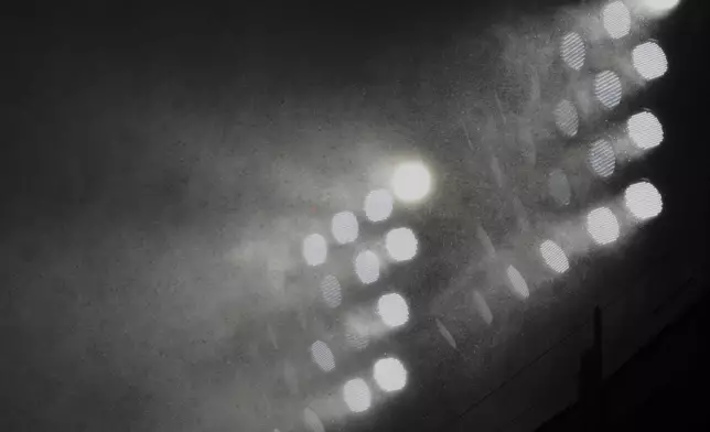 Rain falls on stadium lights during the seventh inning of a baseball game between the Los Angeles Angels and the Chicago White Sox in Chicago, Sunday, March 30, 2025. (AP Photo/Nam Y. Huh)