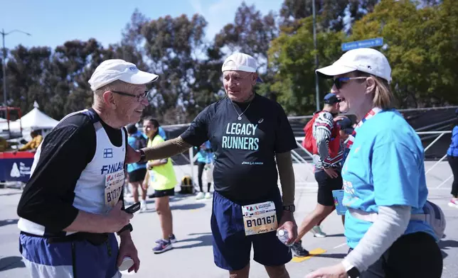 Lou Briones, center, talks to fellow runner Jussi Hamalainen, left, after they both finished the LA Marathon Sunday, March 16, 2025, in Los Angeles. (AP Photo/Eric Thayer)