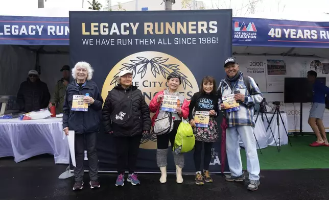 From left, runners Masako Higuchi, 83, third from left, and May DuBois, fourth from left, take photos with fellow runners ahead of the Los Angeles Marathon at the Lifestyle Expo at Dodger Stadium, Friday, March 14, 2025 in Los Angeles. (AP Photo/Damian Dovarganes)