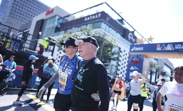 Cliff Housego, center, is hugged by Nancy la Scala after he finished the LA Marathon Sunday, March 16, 2025, in Los Angeles. (AP Photo/Eric Thayer)