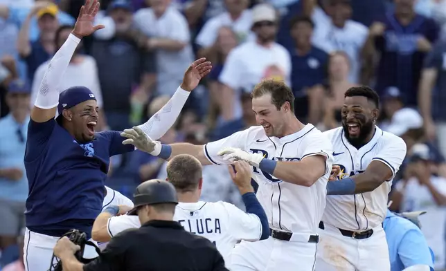 Tampa Bay Rays' Kameron Misner, second from right, celebrates with Christopher Morel, left, Jonny DeLuca and Junior Caminero after hitting a walk-off home run off Colorado Rockies pitcher Victor Vodnik during the ninth inning of a baseball game Friday, March 28, 2025, in Tampa, Fla. (AP Photo/Chris O'Meara)