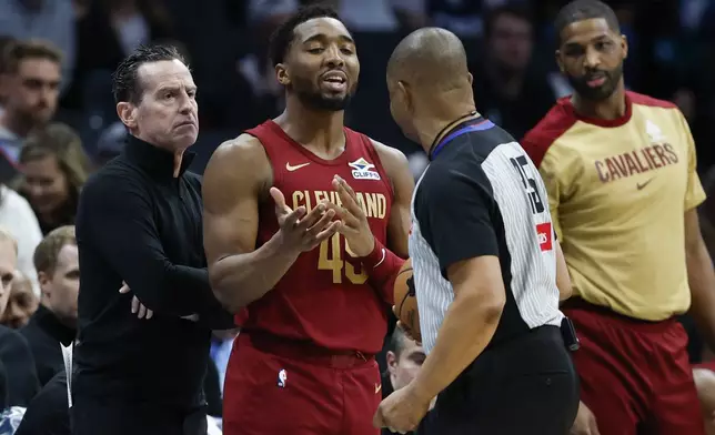 Cleveland Cavaliers guard Donovan Mitchell (45) steps between head coach Kenny Atkinson, left, and referee Tony Brothers, front right, during the first half of an NBA basketball game against the Charlotte Hornets in Charlotte, N.C., Friday, March 7, 2025. (AP Photo/Nell Redmond)