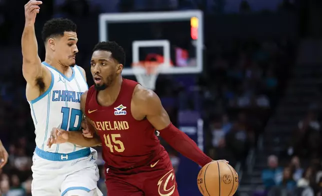 Cleveland Cavaliers guard Donovan Mitchell (45) drives into Charlotte Hornets guard Josh Green, left, during the first half of an NBA basketball game in Charlotte, N.C., Friday, March 7, 2025. (AP Photo/Nell Redmond)