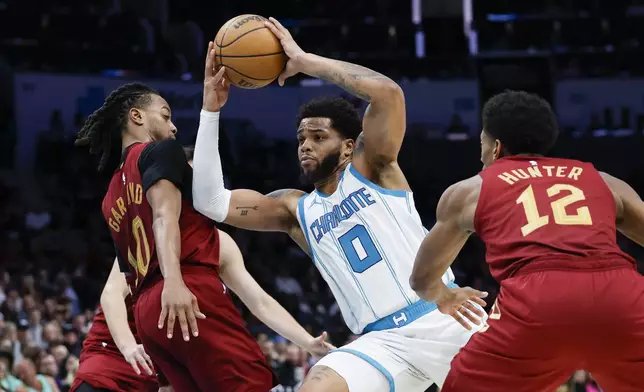 Charlotte Hornets forward Miles Bridges (0) drives to the basket between Cleveland Cavaliers guard Darius Garland (10) and forward De'Andre Hunter (12) during the second half of an NBA basketball game in Charlotte, N.C., Friday, March 7, 2025. (AP Photo/Nell Redmond)