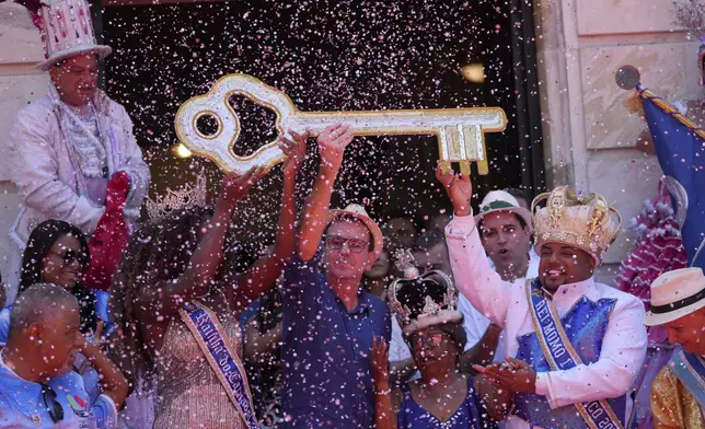 Carnival King Momo, Kaio Mackenzie, right, with Queen Thuane de Oliveira, hold up the keys of the city from Mayor Eduardo Paes, center, at a ceremony officially kicking off Carnival in Rio de Janeiro, Brazil, Friday, Feb. 28, 2025. (AP Photo/Silvia Izquierdo)