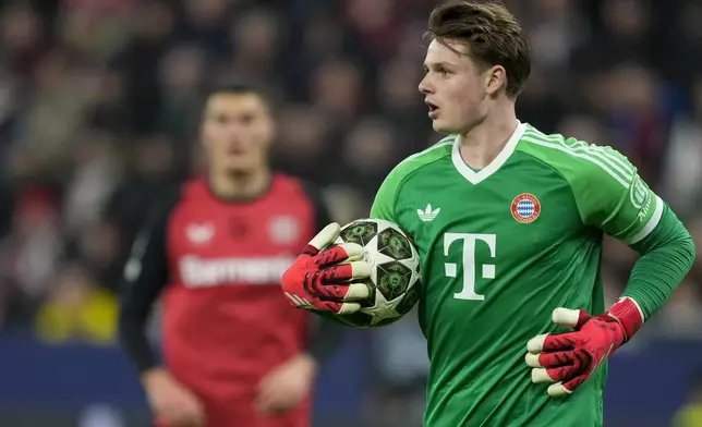 Bayern's goalkeeper Jonas Urbig holds the ball during the Champions League round of 16 second leg soccer match between Bayer Leverkusen and Bayern Munich at the BayArena in Leverkusen, Germany, Tuesday, March 11, 2025. (AP Photo/Martin Meissner)
