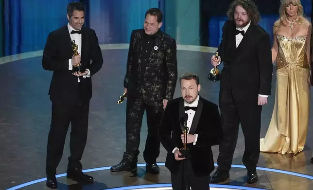 Gregory Zalcman, from left, Ron Dyens, Gints Zilbalodis, center, and Matiss Kaza accept the award for best animated feature film for "Flow" during the Oscars on Sunday, March 2, 2025, at the Dolby Theatre in Los Angeles. Goldie Hawn looks on from right. (AP Photo/Chris Pizzello)