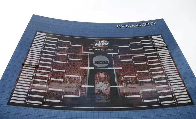 FILE - FILE- In this March 16, 2015, file photo, workers add team names to a 2015 NCAA Division I men's basketball tournament bracket that is displayed on the side of the JW Marriott in Indianapolis. (AP Photo/Darron Cummings, File)