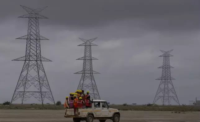 FILE - Workers travel in a vehicle toward the construction site of Adani Green Energy Limited's Renewable Energy Park in the salt desert of Karim Shahi village, near Khavda, Bhuj district near the India-Pakistan border in the western state of Gujarat, India, on Sept. 21, 2023. (AP Photo/Rafiq Maqbool, File)