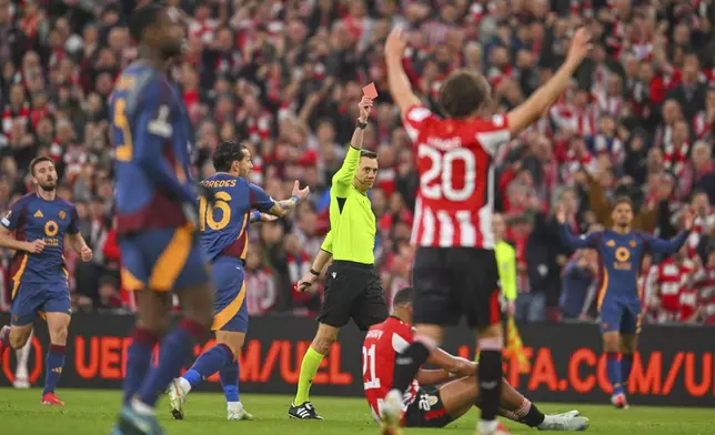 Referee Clement Turpin shows a red card to Roma's Mats Hummels, unseen, during the Europa League round of 16 second leg soccer match between Athletic Bilbao and AS Roma at the San Mames stadium in Bilbao, Spain, Thursday, March 13, 2025. (AP Photo/Miguel Oses)