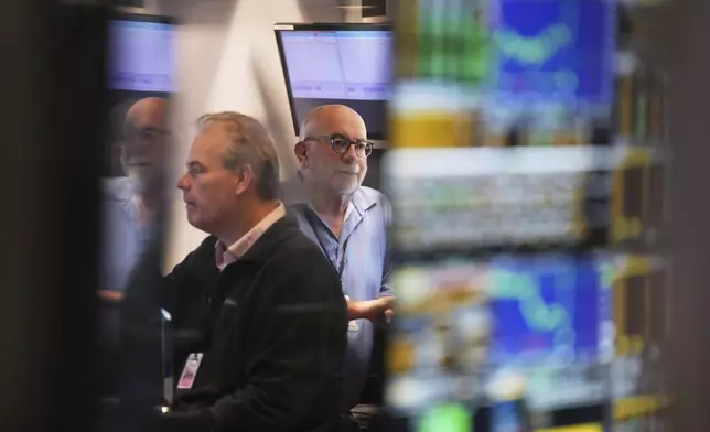 People work on the floor at the New York Stock Exchange in New York, Monday, March 24, 2025. (AP Photo/Seth Wenig)