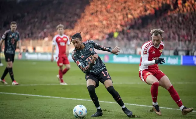 Bayern's Michael Olise challenges for the ball with Union's Benedict Hollerbach during the Bundesliga soccer match between Bayern Munich and Union Berlin at the An der Alten Forsterei stadium in Berlin, Germany, Saturday, March 15, 2025. (AP Photo/Ebrahim Noroozi)