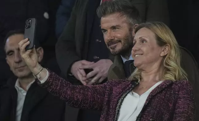 Former England soccer player David Beckham, center, poses for a photo with a spectator before the Champions League round of 16 first leg soccer match between Paris Saint-Germain and Liverpool at the Parc des Princes in Paris, Wednesday, March 5, 2025. (AP Photo/Aurelien Morissard)