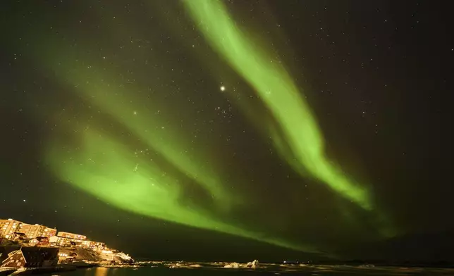 The northern lights appear over homes in Nuuk, Greenland, Monday, Feb. 17, 2025. (AP Photo/Emilio Morenatti)