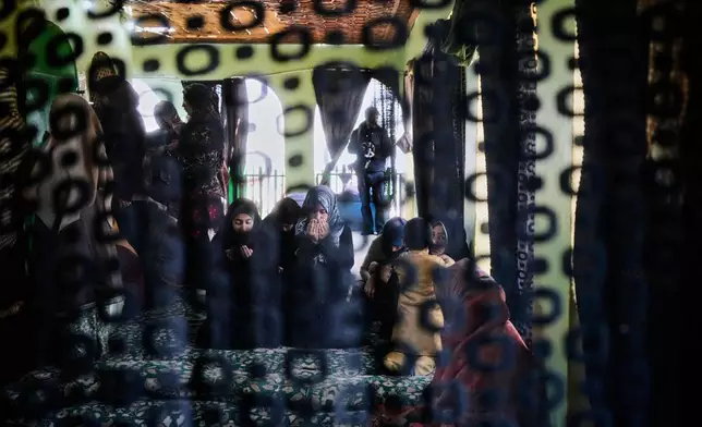 Shiite Muslim women pray on the other side of a curtain at the shrine of Peer Syed Mehndi on Nowruz, Persian New Year, in Srinagar, Indian controlled Kashmir, Friday, March 21, 2025. (AP Photo/Mukhtar Khan)