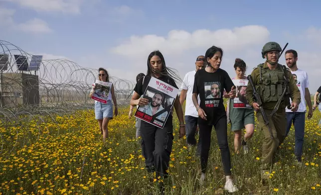 Relatives of hostage held by Hamas in the Gaza Strip, attempt to approach the Gaza border, escorted by Israeli soldiers, calling for their release and expressing concerns that the resumption of fighting in Gaza puts their loved ones at risk, in southern Israel, Tuesday, March 18, 2025. (AP Photo/Ohad Zwigenberg)