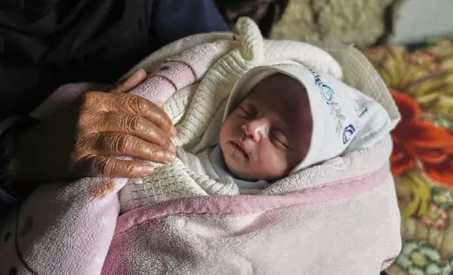 Ella Osama Abu Dagga, 25 days old, is held by her great-aunt Suad Abu Dagga, after she was pulled from the rubble earlier following an Israeli army airstrike that killed her parents and brother, in Khan Younis, southern Gaza Strip, Thursday, March 20, 2025. (AP Photo/Abdel Kareem Hana )