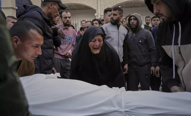 A woman reacts over the body of a person killed during overnight Israeli army airstrikes across the Gaza Strip, at the Al-Ahli hospital in Gaza City, Tuesday, March 18, 2025. (AP Photo/Jehad Alshrafi)