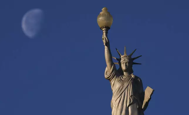 A replica of the Statue of Liberty stands at an RV Park in Waco, Texas, as the moon is in its waning gibbous stage, Thursday, March 20, 2025. (AP Photo/Julio Cortez)