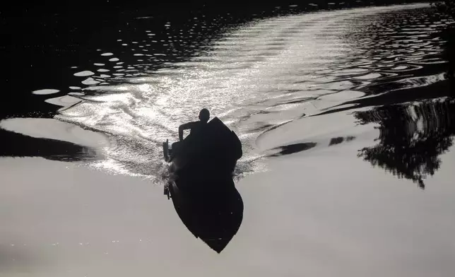 A youth navigates a motor boat on the Rio Caxiuana near Brazil's Ferreira Penna Scientific Station, in Para state, Friday, March 21, 2025. (AP Photo/Jorge Saenz)