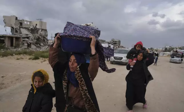 Displaced Palestinians, carrying their belongings, move away from the areas where the Israeli army is operating after Israel's renewed offensive in the Gaza Strip, on the outskirts of Beit Lahia, Thursday, March 20, 2025. (AP Photo/Jehad Alshrafi)
